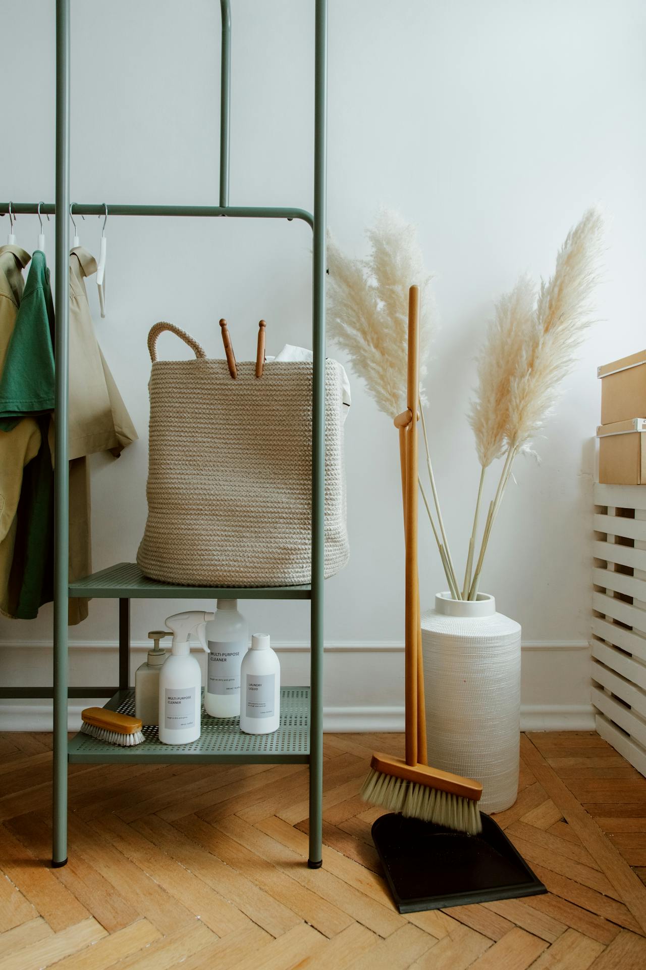 Minimalist cleaning supplies setup with eco-friendly products, a woven basket, and a broom in a stylish home setting.